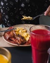 Close-up of hands eating scrambled eggs, bacon, toast and juice Royalty Free Stock Photo