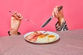 Female hands with fork and knife eating English breakfast with fried eggs and bacon Royalty Free Stock Photo