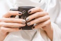 Female hands with glitter nail design holding black cup