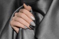 Female hands with glitter silver nail design. Silver nail polish manicure. Woman hands hold grey wool shawl