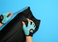 Female hands in gloves hold a bag with a twisted sports mat on a blue background