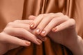 Female hands with gold nail design. Glitter bronze nail polish manicure. Woman hands with bronze fabric background