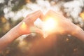 Female hands heart shape on nature bokeh sun light flare and blur leaf abstract background Royalty Free Stock Photo