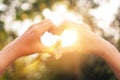 Female hands heart shape on nature bokeh sun light flare and blur leaf abstract background Royalty Free Stock Photo