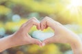 Female hands heart shape on nature bokeh sun light flare and blur leaf abstract background. Copy space of happy love and freedom Royalty Free Stock Photo