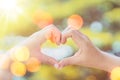 Female hands heart shape on nature bokeh sun light flare and blur leaf abstract background. Copy space of happy love and freedom Royalty Free Stock Photo