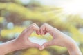 Female hands heart shape on nature bokeh sun light flare and blur leaf abstract background. Copy space of happy love and freedom Royalty Free Stock Photo