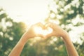 Female hands heart shape on nature bokeh sun light flare and blur leaf abstract background Royalty Free Stock Photo