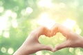 Female hands heart shape on nature green bokeh sun light flare and blur leaf abstract background Royalty Free Stock Photo