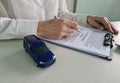 Female hands hold ballpoint pen over car insurance blank and toy car Royalty Free Stock Photo