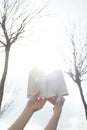 Female hands hold the book against the background of nature. Vertical shot. Royalty Free Stock Photo