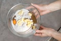 Female hands hold a bowl with unmixed ingredients to bake a cake in a glass bowl. Eggs, flour, margarine in a glass bowl held by a Royalty Free Stock Photo