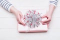 Female hands hold box wrapped in pink paper with bow Royalty Free Stock Photo