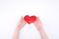 Female hands hold a broken heart on a white background with wedding rings. Relationship problems in marriage, divorce