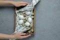 Female hands hold chicken and quail eggs in a wooden box with a towel on a gray concrete background. Top view. Flat lay Royalty Free Stock Photo