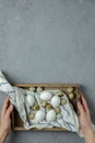 Female hands hold chicken and quail eggs in a wooden box with a towel on a gray concrete background. Top view. Flat lay Royalty Free Stock Photo