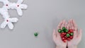 Female hands hold Christmas red green bells on a gray background with New Year\'s big white snowflake decor.