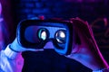 Female hands hold 3d 360 vr headset glasses in futuristic purple neon light