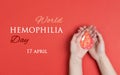 Female hands hold a drop of blood on a red background. World Hemophilia Day background