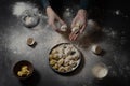 Female hands hold dumplings - Russian dumplings, ravioli with meat in a black plate on a black background.