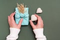 Female hands hold eco friendly furoshiki gift with ears of dry grass and two knitted hearts on a green background Royalty Free Stock Photo