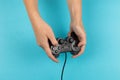 Female hands hold a gamepad on a blue background. Weekend concept, gaming hobby. Copy space