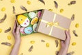 Female hands hold a gift box with Easter homemade gingerbread cookies on yellow background Royalty Free Stock Photo