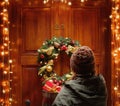 Female hands hold gift boxes in front of the door. Magic on Christmas eve