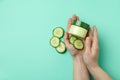 Female hands hold jar with cosmetics on mint background with cucumber slices Royalty Free Stock Photo