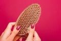 Female hands hold a massage brush, which has a natural wooden handle and wild boar bristles