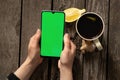 Female hands hold a mobile phone and a cup of tea with lemon on an old wooden table Royalty Free Stock Photo