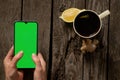 Female hands hold a mobile phone and a cup of tea with lemon on an old wooden table Royalty Free Stock Photo