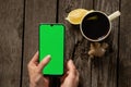 Female hands hold a mobile phone and a cup of tea with lemon on an old wooden table Royalty Free Stock Photo