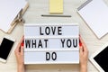 Female hands hold modern board with `Love what you do` word over