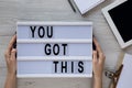 Female hands hold modern board with text `You got this`. Feminine workspace. Business concept. Overhead, top view, from above. Royalty Free Stock Photo