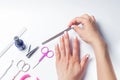 Female hands hold a nail file, next to lay down devices for nail care. The girl does a manicure. on white background. View from Royalty Free Stock Photo