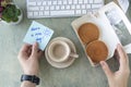 female hands hold note with words HAVE A NICE DAY, pancakes in paper box, cup of coffee, keyboard, cactus and mause on a Royalty Free Stock Photo