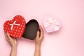Female hands hold a paper red box in the shape of a heart on a pink background Royalty Free Stock Photo