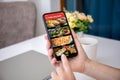 female hands hold phone with food delivery application on screen