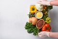 Female hands hold plastic box with assortment of fresh vegetables, fruits, cereals and seeds on old wooden background. Safe home d Royalty Free Stock Photo