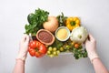 Female hands hold plastic box with assortment of fresh vegetables, fruits, cereals and seeds on old wooden background. Safe home d Royalty Free Stock Photo