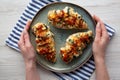 Female hands hold a plate with homemade Hasselback chicken, top view. Flat lay, overhead, from above