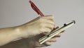 Female hands hold a red pen and take notes in a small notebook