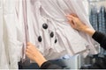 Female hands hold shirts in hangers in store. Woman shoose some clothes, close up.