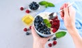 Female hands hold a spoon and bowl with cottage cheese and fresh berries. Healthy breakfast in the morning. ?lose-up. Copy space. Royalty Free Stock Photo