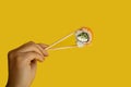 Female hands hold sushi rolls with chopsticks. Yellow background. creative concept Royalty Free Stock Photo