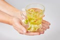 Female hands hold a transparent glass mug with linden tea