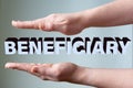 Female hands hold the word BENEFICIARY on a light background