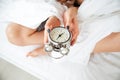 Female hands holding alarm clock on the bed Royalty Free Stock Photo