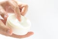 Female hands holding and apply jar of nourishing cream on white background.Skin care and beauty concept.Closeup